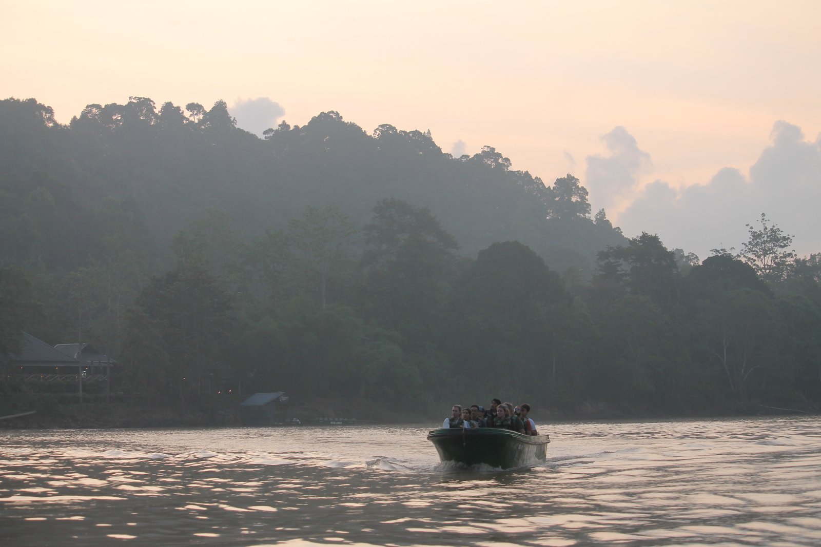 A small safari boat on the Kinabatangan River at sunrise