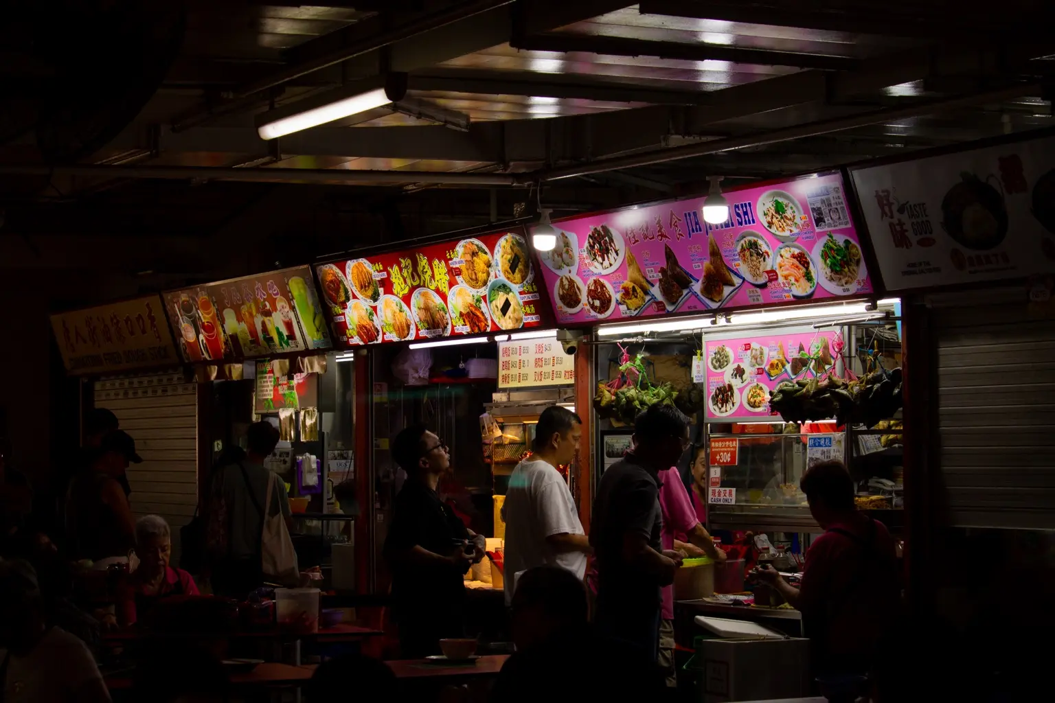 Bright food stalls and diners inside a Singapore hawker centre