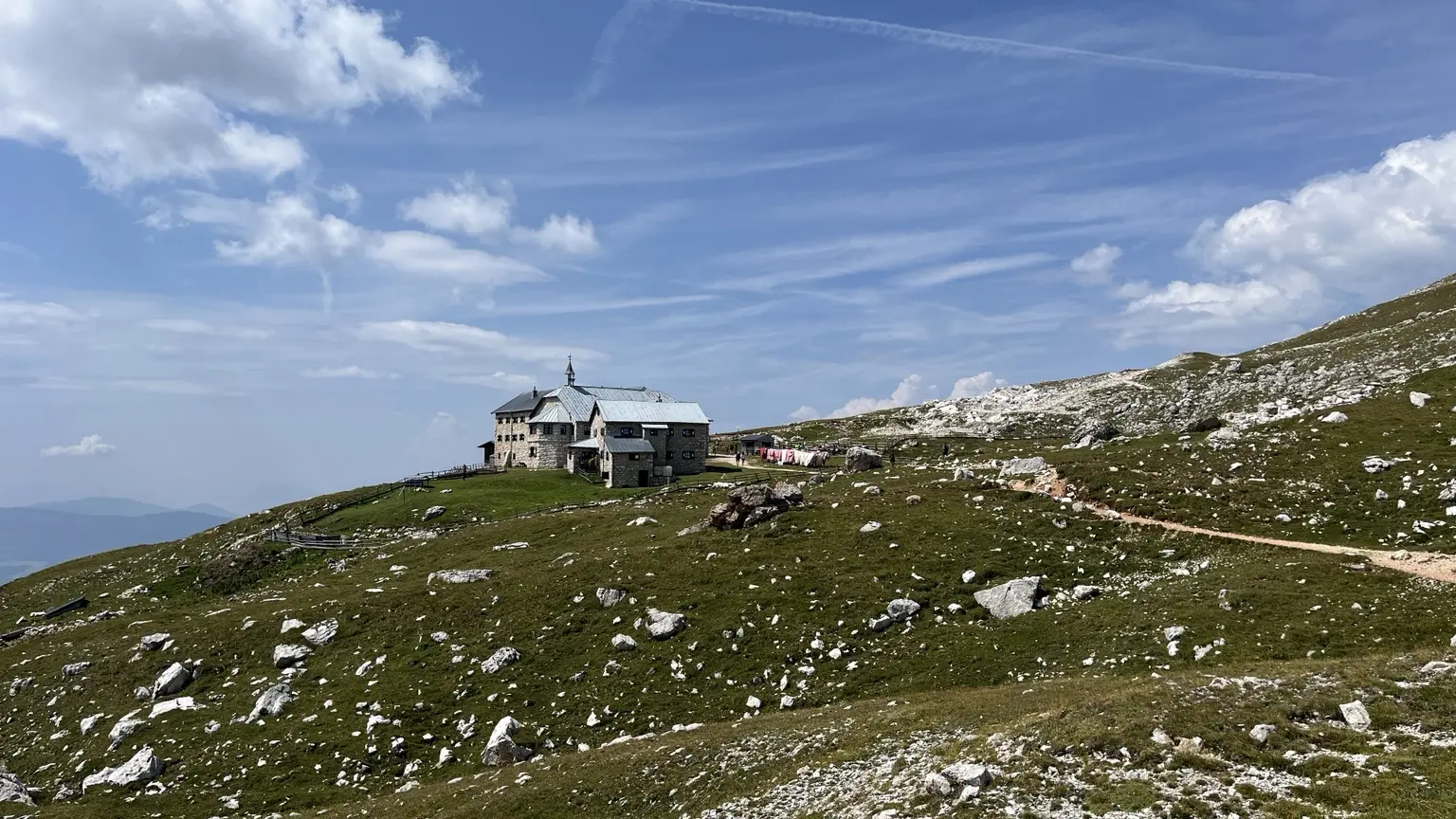 Schlernhaus on a green plateau between pale rocks and a wide sky