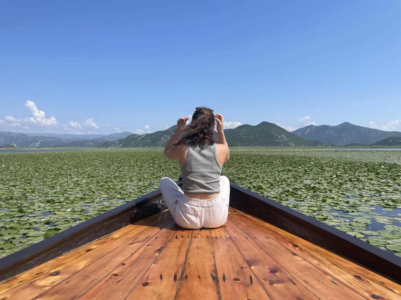 Woman on the bow of a wooden boat among water lilies on Lake Skadar