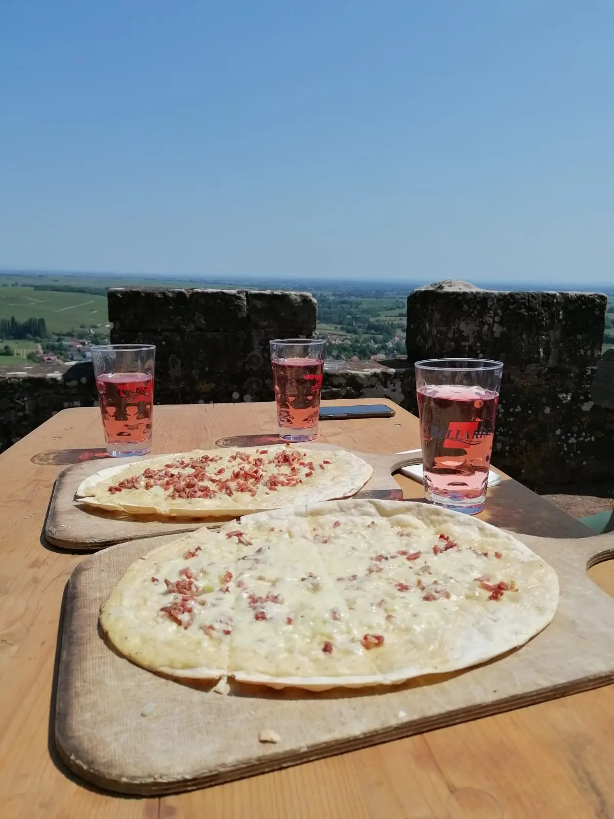 Two tarte flambées and three Palatinate wine spritzers on a castle terrace with a wide view