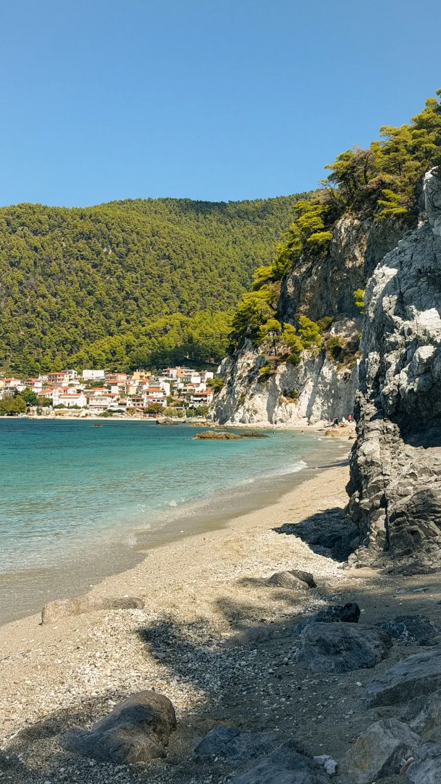 Turquoise water beneath green cliffs at Hovolo Beach