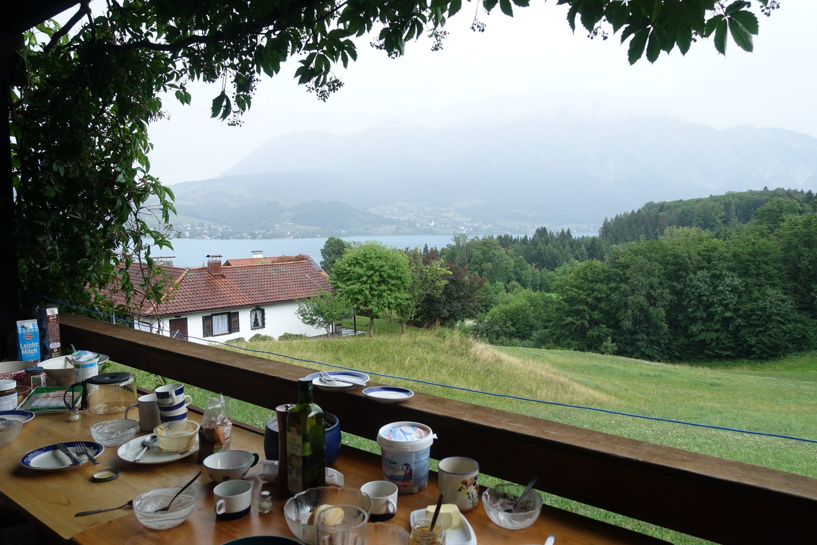 Breakfast table on a terrace overlooking Lake Attersee and forested mountains