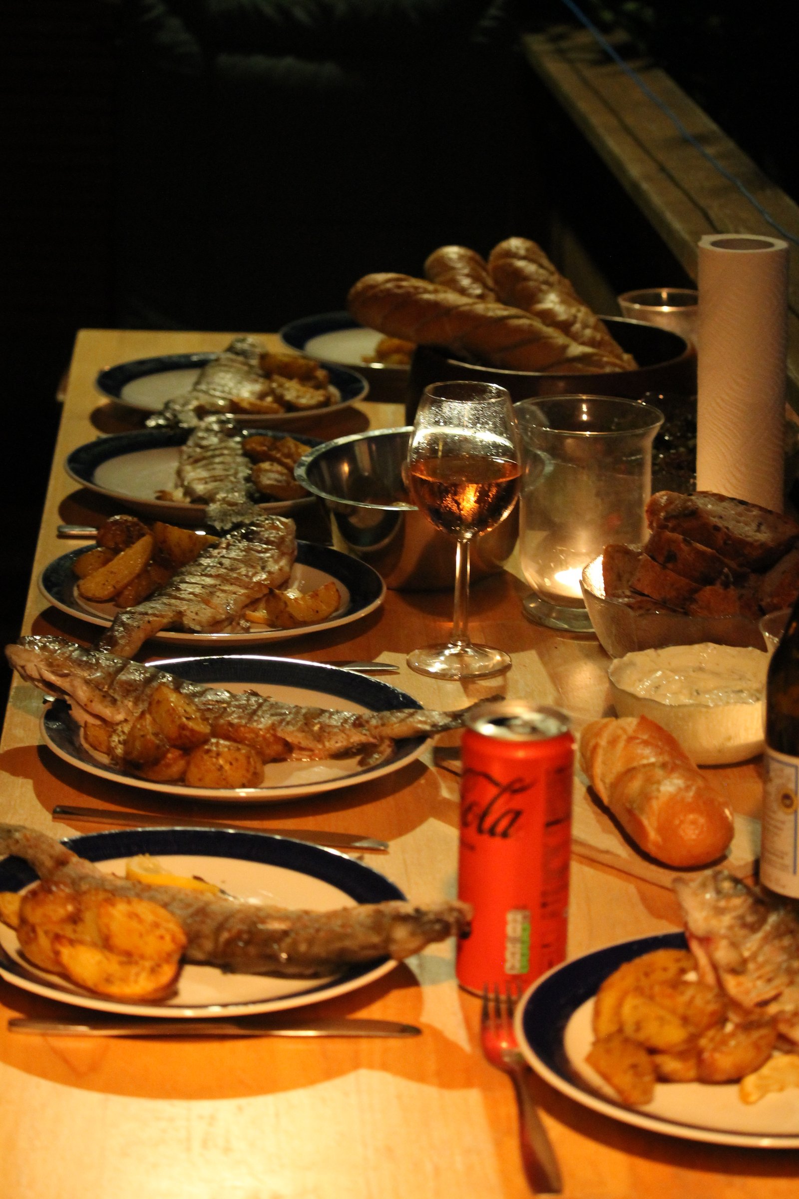 Grilled fish, potatoes, bread and wine on a long table at Lake Attersee