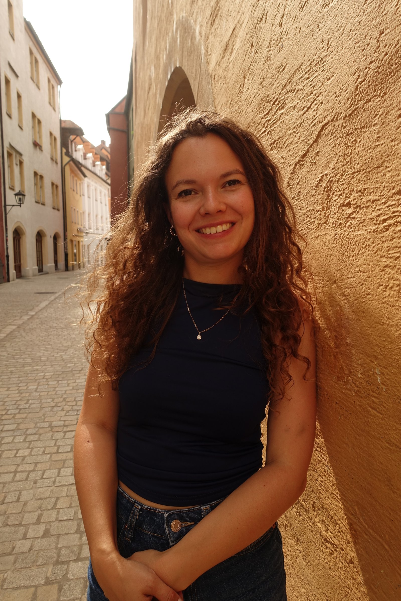 Anna smiling in a sunlit old-town street