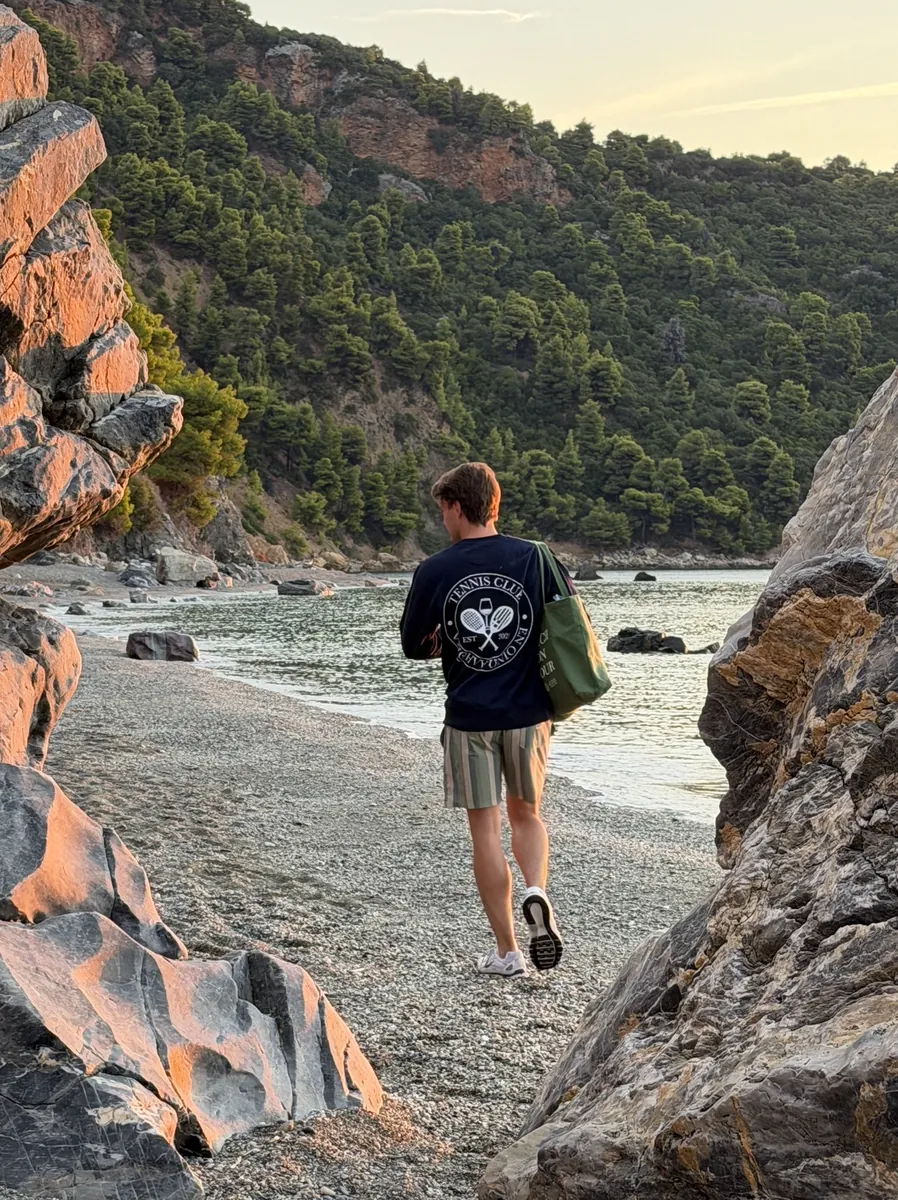 Tennis Club Greece sweatshirt worn on a beach at sunset